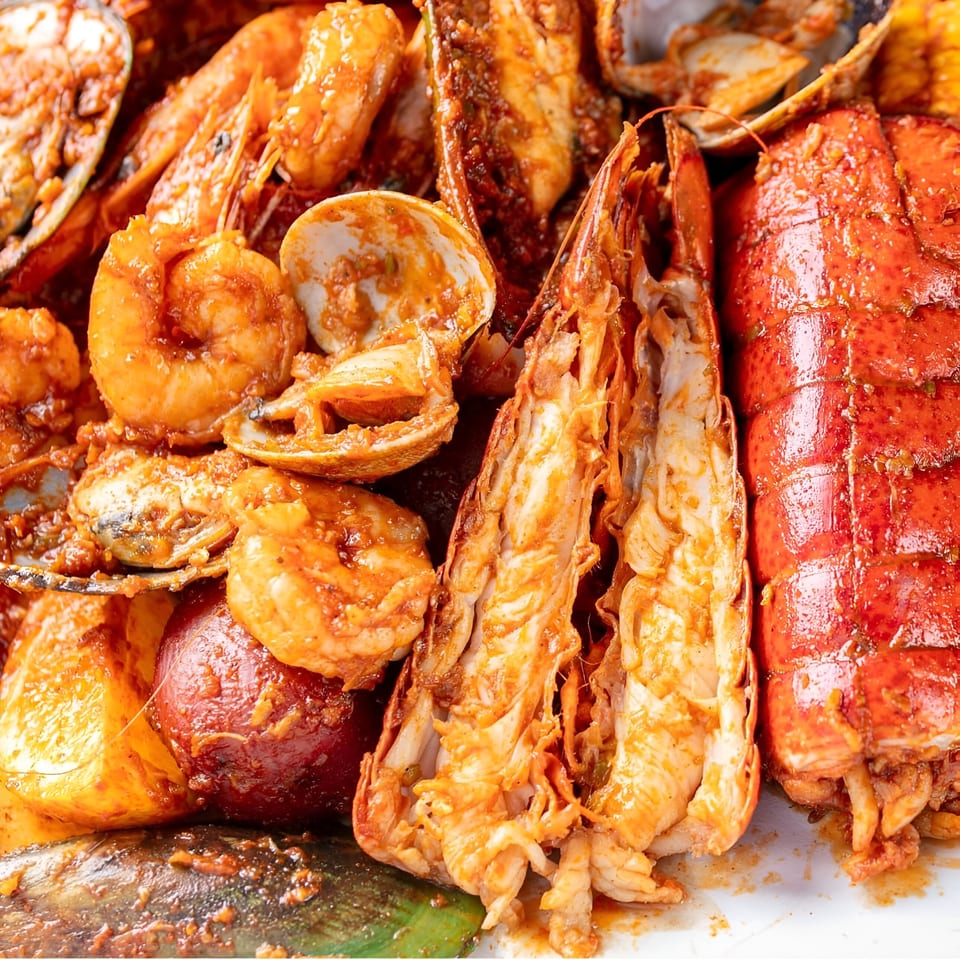 Close-up of a Boil Daddy seafood boil with lobster, shrimp, clams, and potatoes.