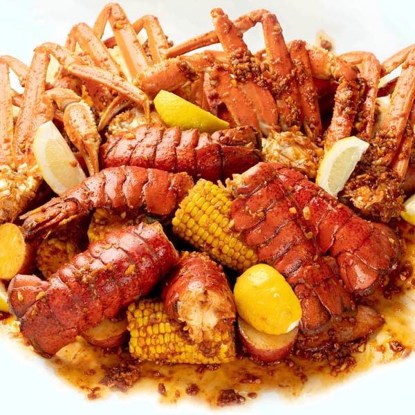 Boil Daddy's seafood boil with snow crab legs, lobster tails, corn, potatoes, and lemon wedges.